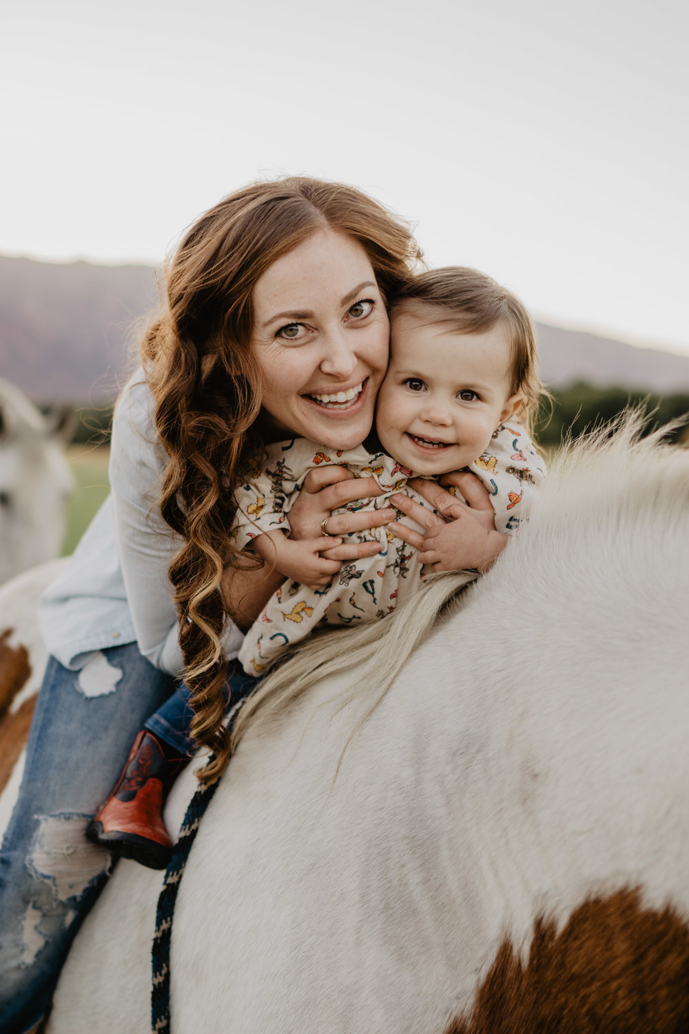 mother and young child on a horse together smiling