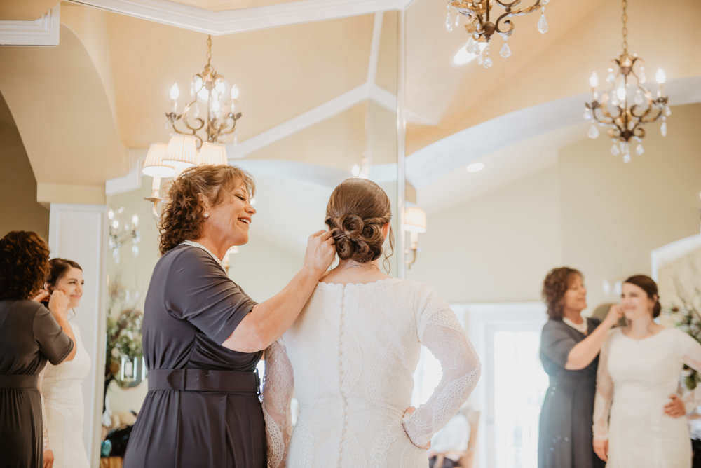 mom helping her daughter getting ready in a beautiful brides room at her Teton wedding venue