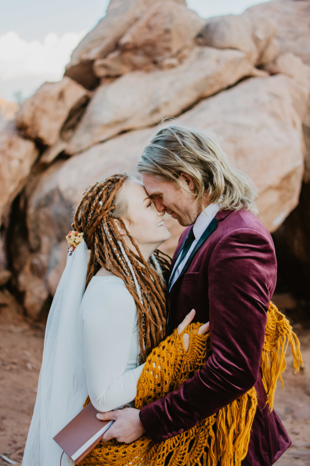 Moab Utah adventure elopement with bride and groom embracing each other and smiling as their noses touch while standing in front of red rocks Jocilyn Bennett Photography | How to Plan an Elopement | Why Elope | Reasons to Elope | Destination Wedding Photographer | Utah Wedding Photographer | Adventure Photographer | Destination Elopement Photographer | Traveling Photographer | Arches National Park | Arches National Park Elopement | Southern Utah Elopement | Boho Bride | Bride with dreads |
