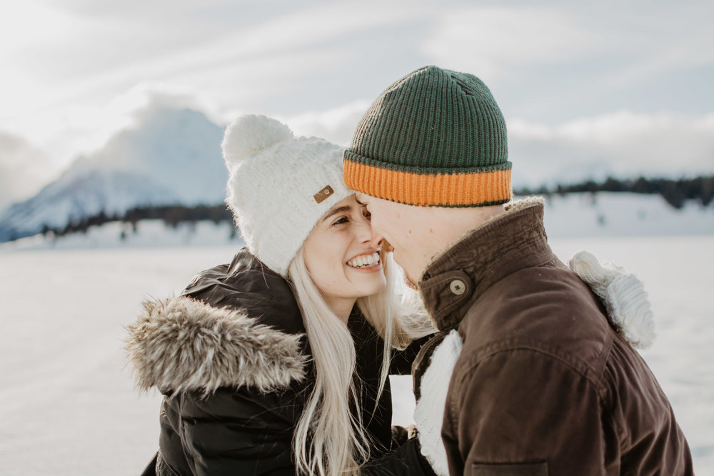 woman with her forehead to the mans head, making their noses touch as she smiles and laugh, they are in the Grand Tetons | Jocilyn Bennett Photography | Winter Engagements | Snowy Engagements | Wyoming Engagement Photography | Utah Wedding Photographer | Winter Engagement Poses | What to Wear for Winter Engagements | Destination Wedding Photographer | Outfit ideas for Winter Engagements | Adventure Photographer | Wyoming Photographer | Winter Engagements in Jackson Hole | Jackson Hole Engagements | Wyoming Bride | Wyoming Wedding Photographer | Jackson Hole Wedding Photographer |