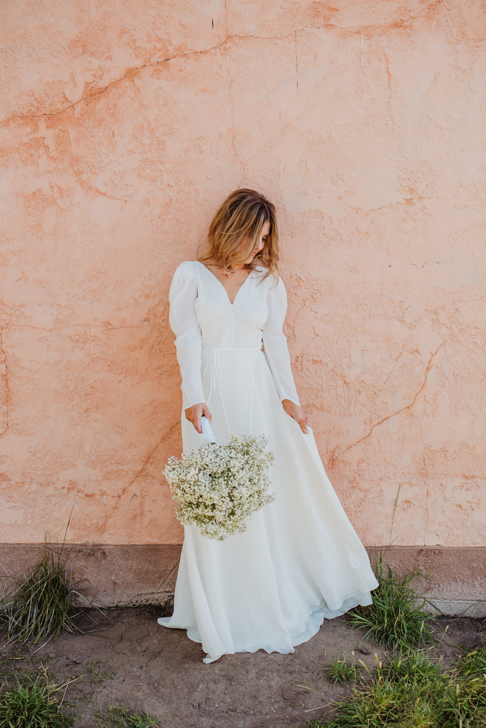 bride looking down at her simple white wedding gown as she holds her wedding bouquet and smiles in Jackson Hole Jocilyn Bennett Photography | How to Plan an Elopement | Why Elope | Reasons to Elope | Destination Wedding Photographer | Utah Wedding Photographer | Adventure Photographer | Destination Elopement Photographer | Traveling Photographer | Grand Teton Elopement | Grand Teton Photographer | National Park Weddings | Mountain elopement |