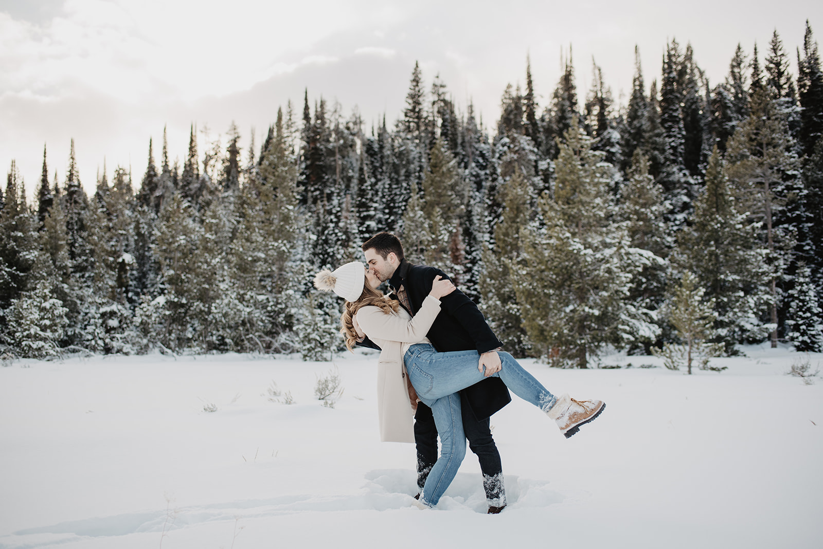 winter engagement session in Jackson Hole with man dipping the woman and holding her leg while kissing passionately