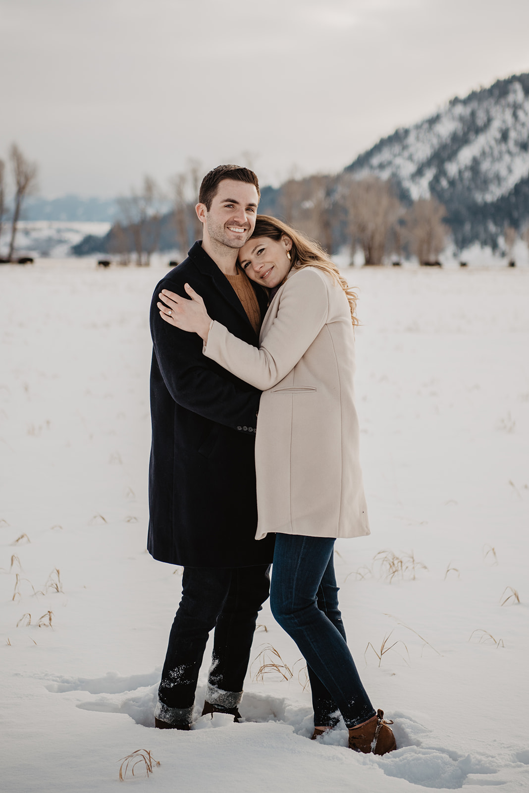 man and woman standing a field of snow in Jackson Hole for their winter engagement session