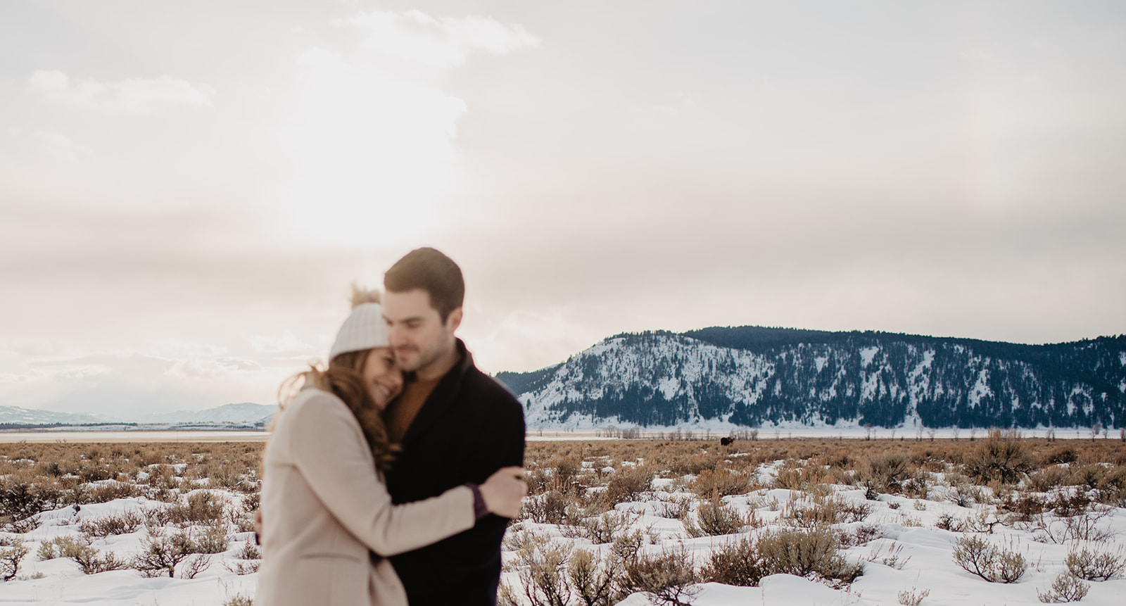 out of focus picture of woman holding a man in Jackson Hole for a winter engagement session