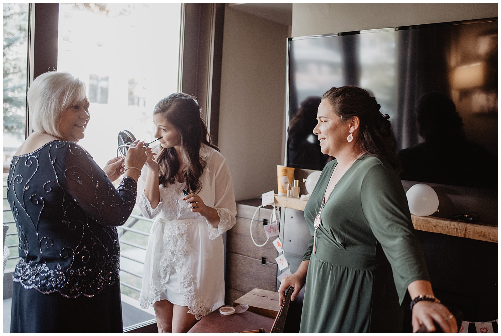 bride getting ready with her sisters and mother in a lodge for her fall wedding in the Tetons