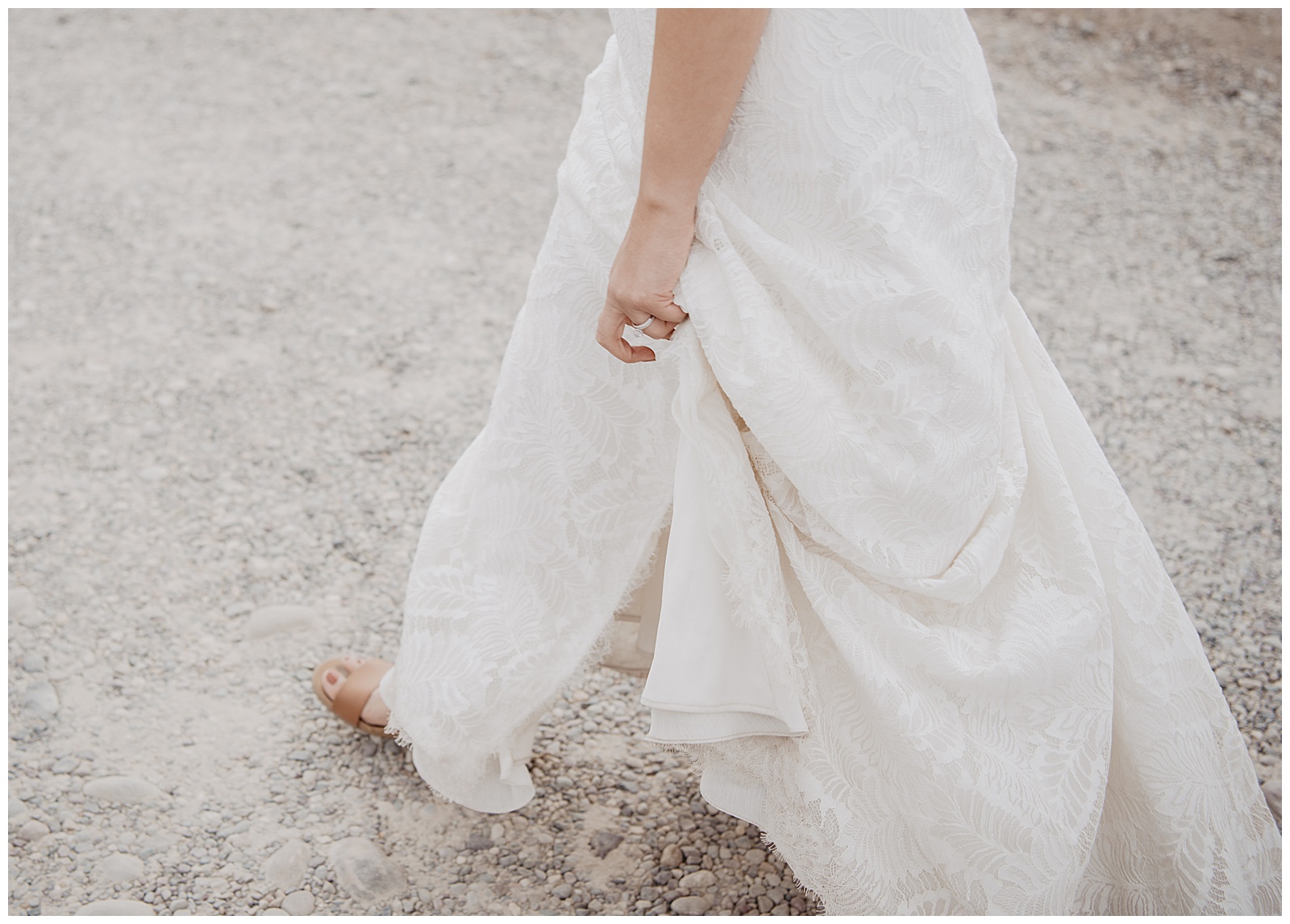 detail shot of the bride walking while holding up her lace gown so that it doesn't drag on the gravel floor in the Tetons