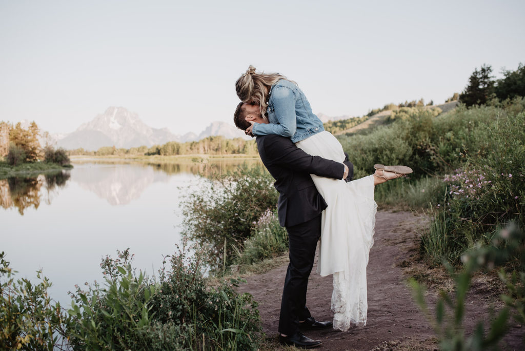 jackson hole photographers captures groom kifting his bride up and kissing her at their sunrise session for their elopement 
