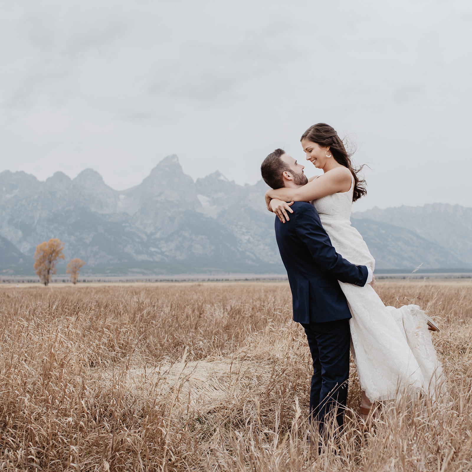 groom lifting up his bride as they dance in front of the Grand Tetons at their Jackson Hole wedding venue