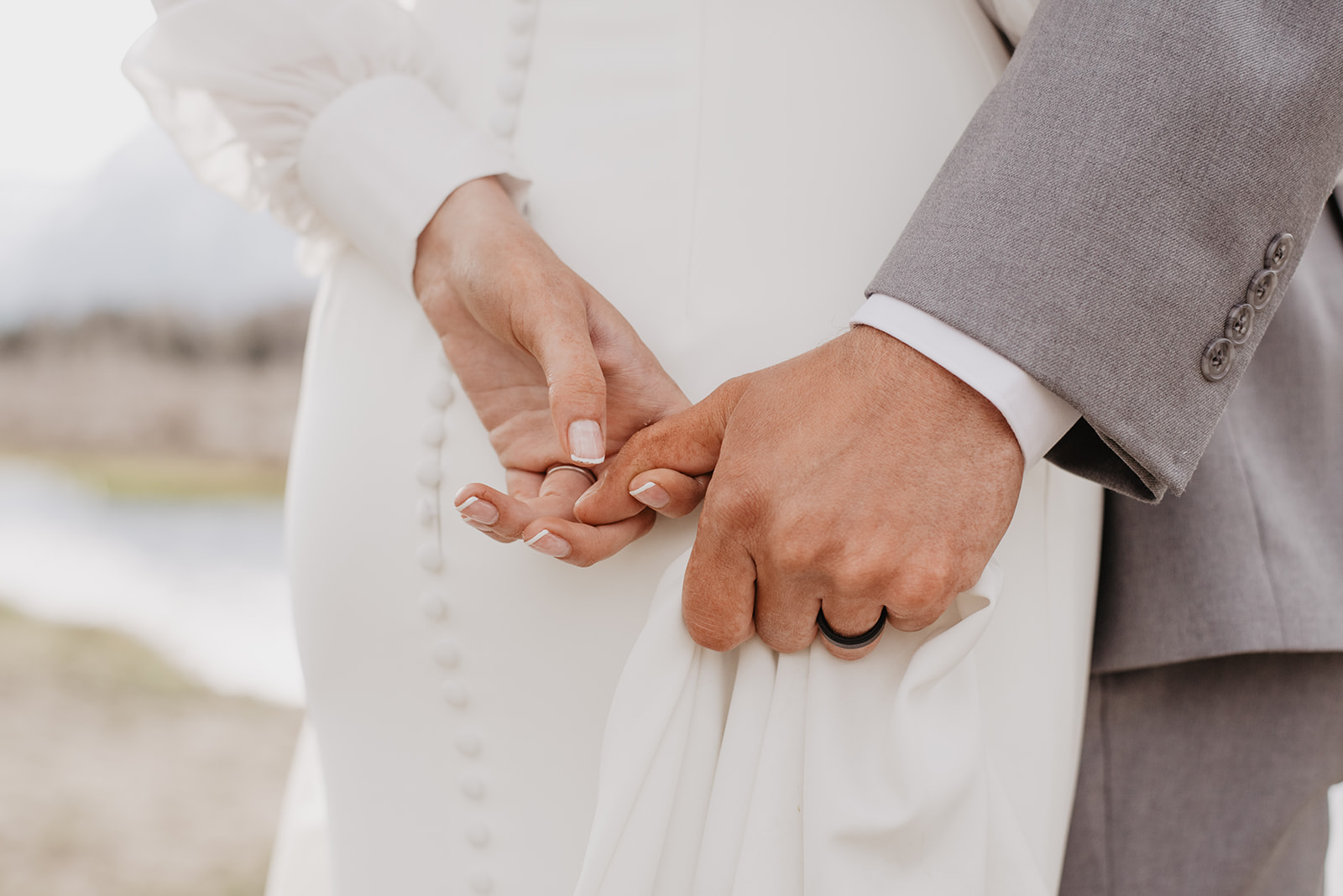 detail shot of bride and groom holding hands behind their backs for their Jackson Hole wedding