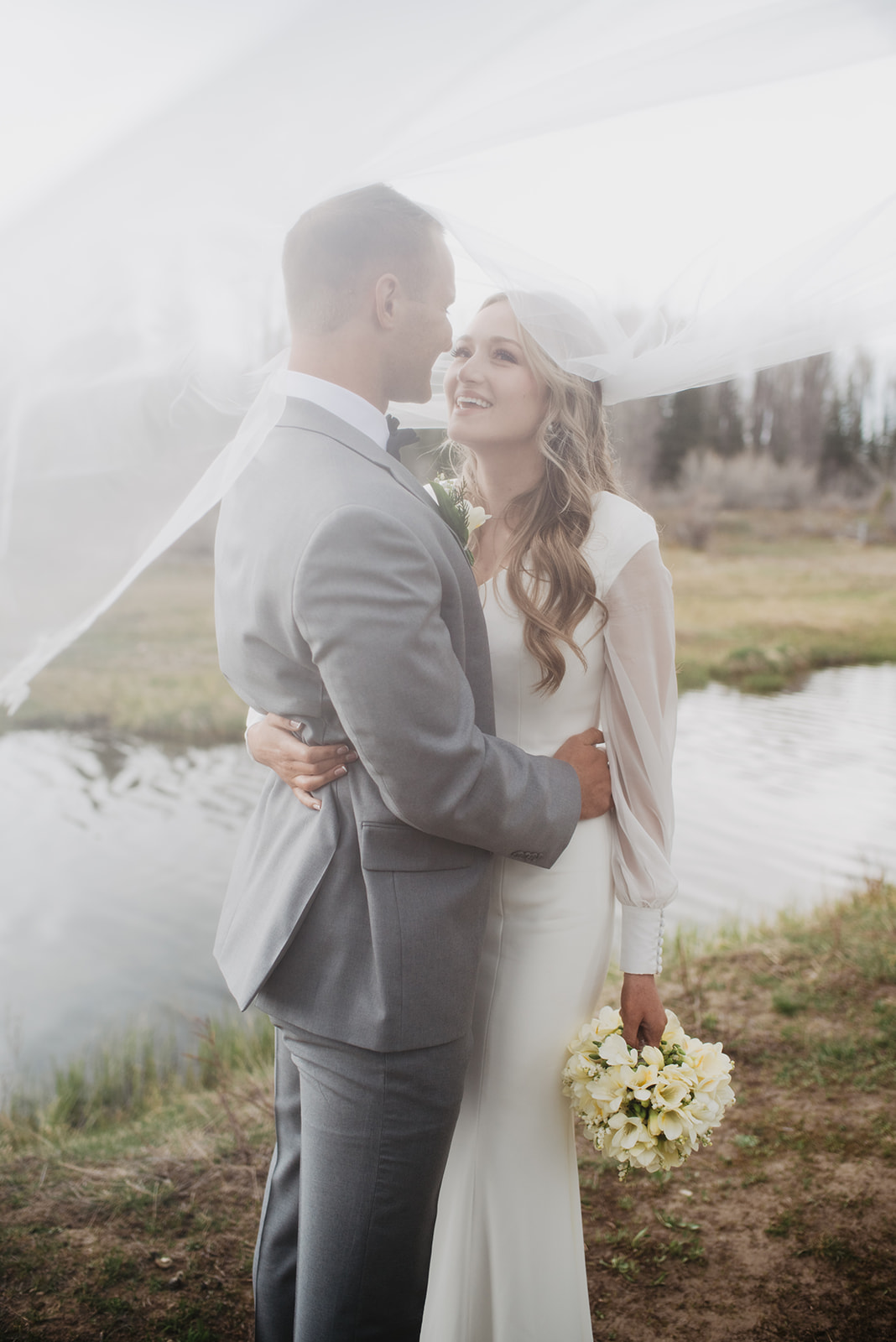 bridal portraits with husband and wife on their wedding day in the foggy mountains of the Tetons mountain range holding each other romantically