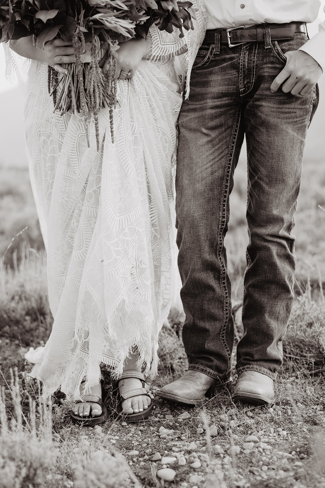 black and white image of man and woman on their wedding day standing in a field, close up of just their legs