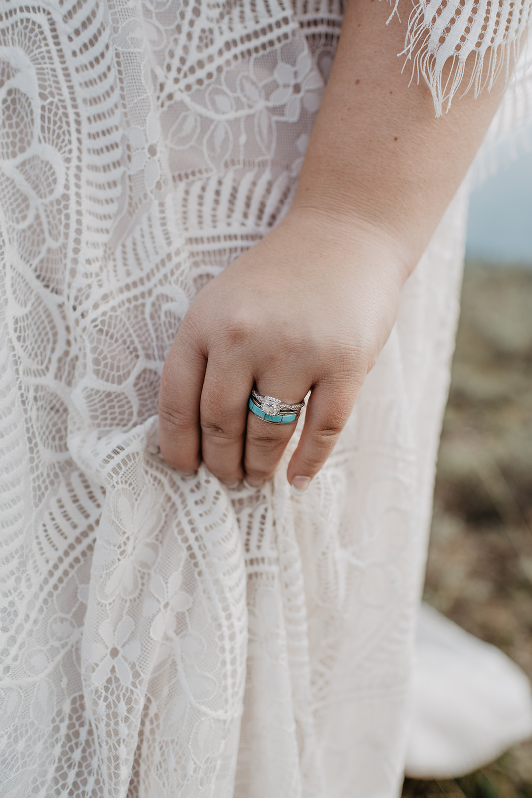 detail shot of bride's engagement ring and turquoise wedding band by her vintage lace wedding dress