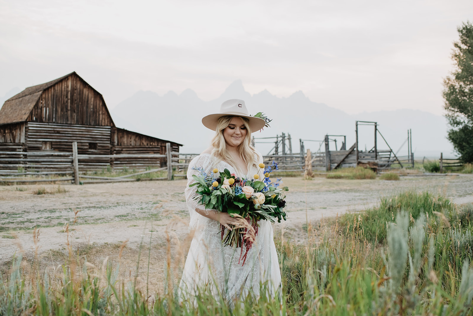 bride walking through a field in front of an old historic barn on her wedding day