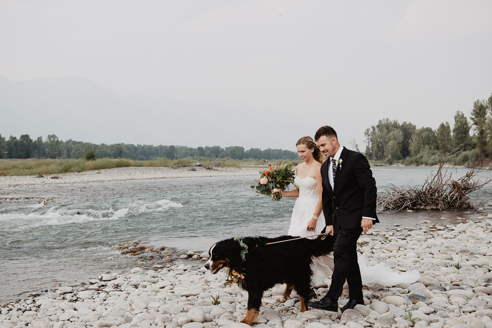 bride and groom walking on a rocky river bed with their dog for their Jackson Hole elopement