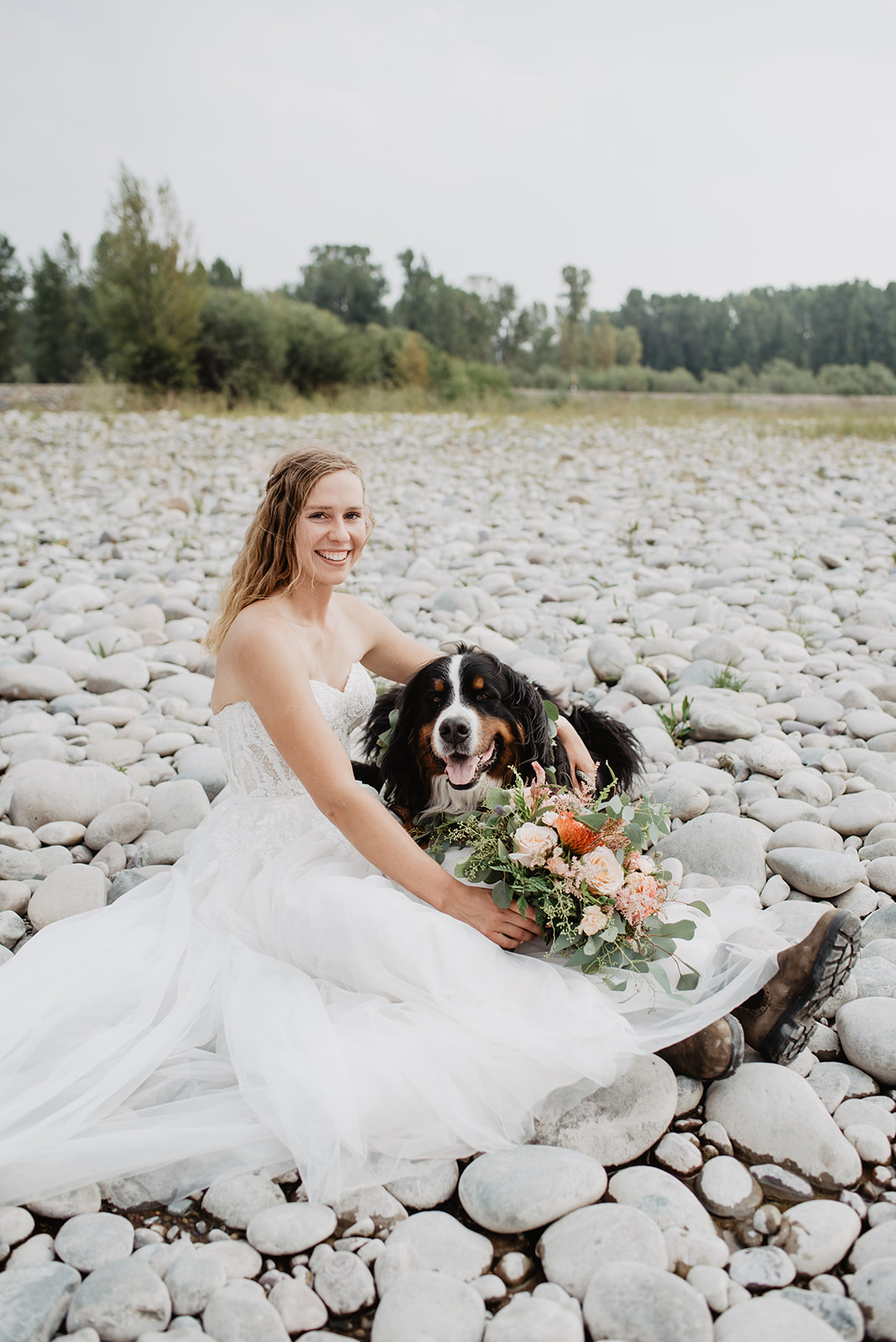 bride sitting on the river rock bed with her dog for her Jackson Hole elopement