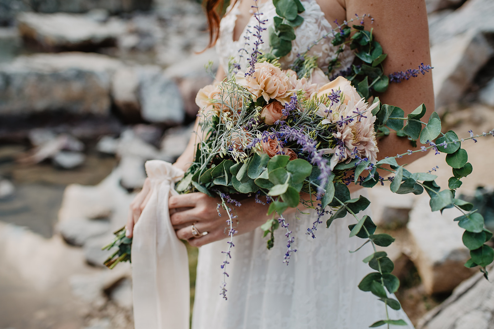 bride carrying a beautiful floral DIY wedding bouquet that is wrapped in light pink cloth with wild and native florals in the Grand Tetons