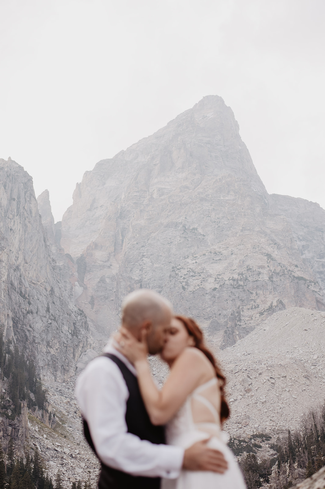 elopement in the Fall in the Grand Tetons with a bride and groom kissingwith a huge mountain behind them, the focus of the picture being the Teton mountain