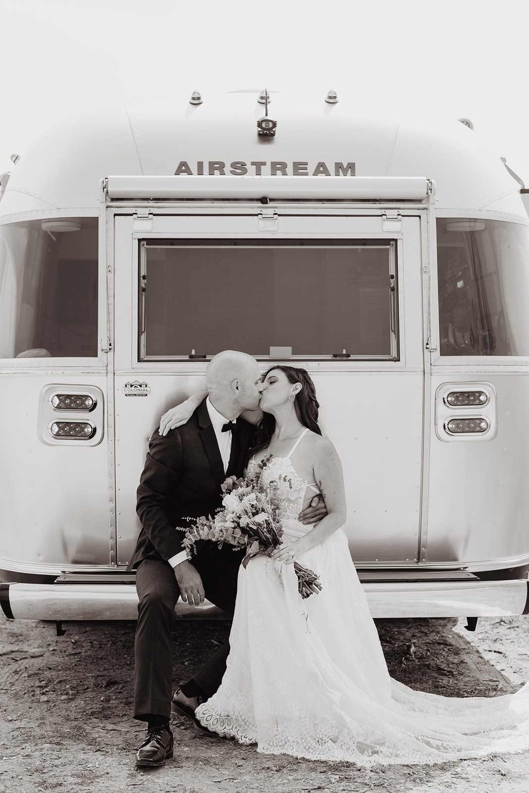 black and white image of bride and groom sitting on the back of their airstream kissing each other for their fall elopement in the Tetons