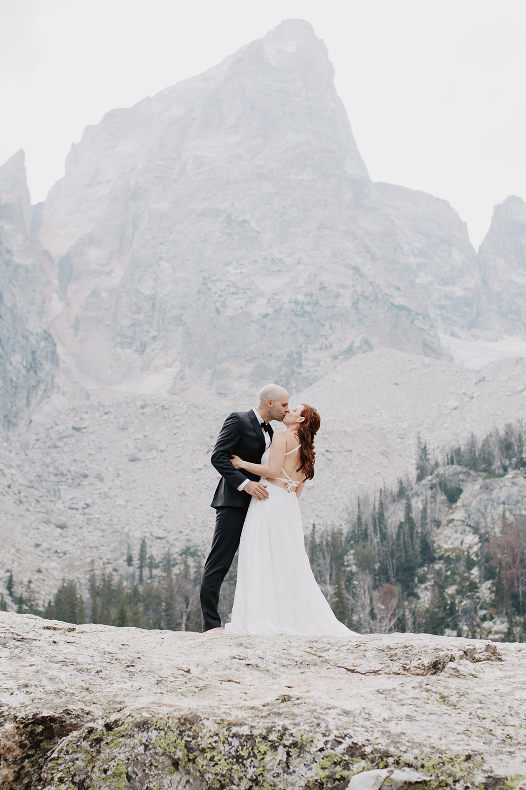 wedding day couple stannding on a rock in the fall in the Tetons kissing to celebrate their elopement