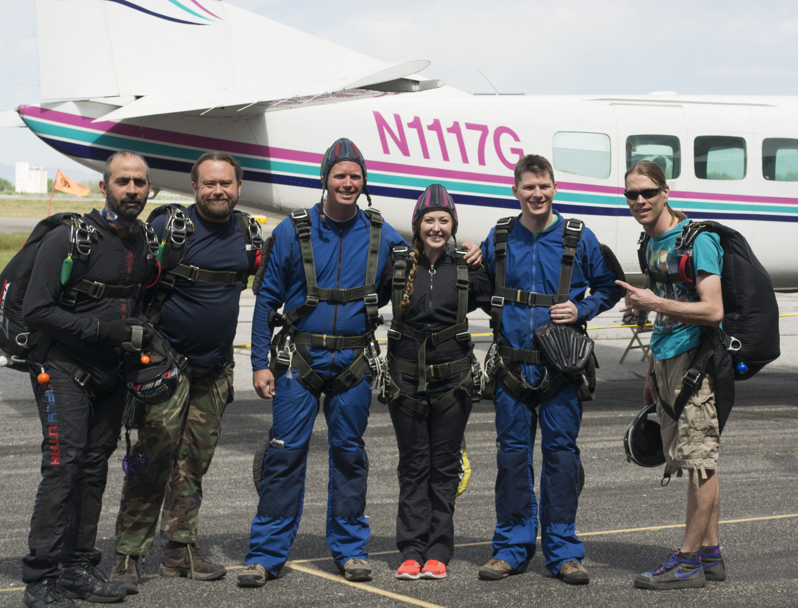 group of friends standning outside of an airplane before they go skydiving with an adventure elopement photographer