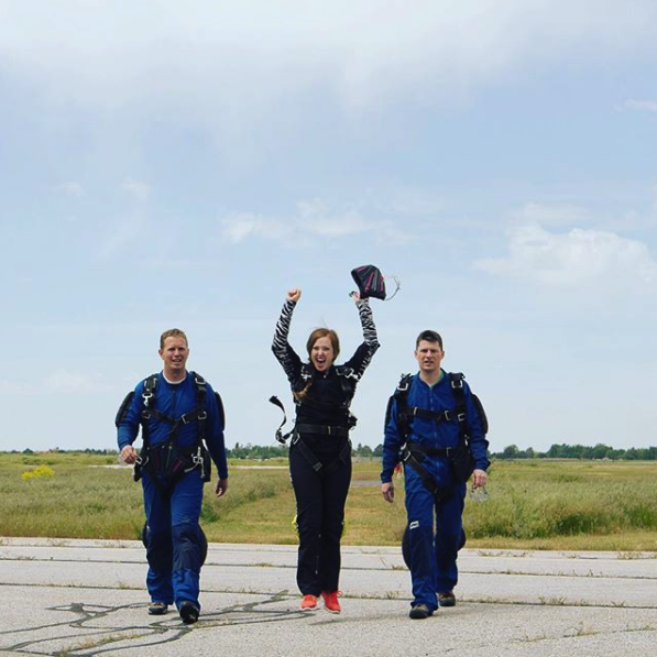 adventure elopement photographer goes skydiving as she walks to the plane with her hands in the air