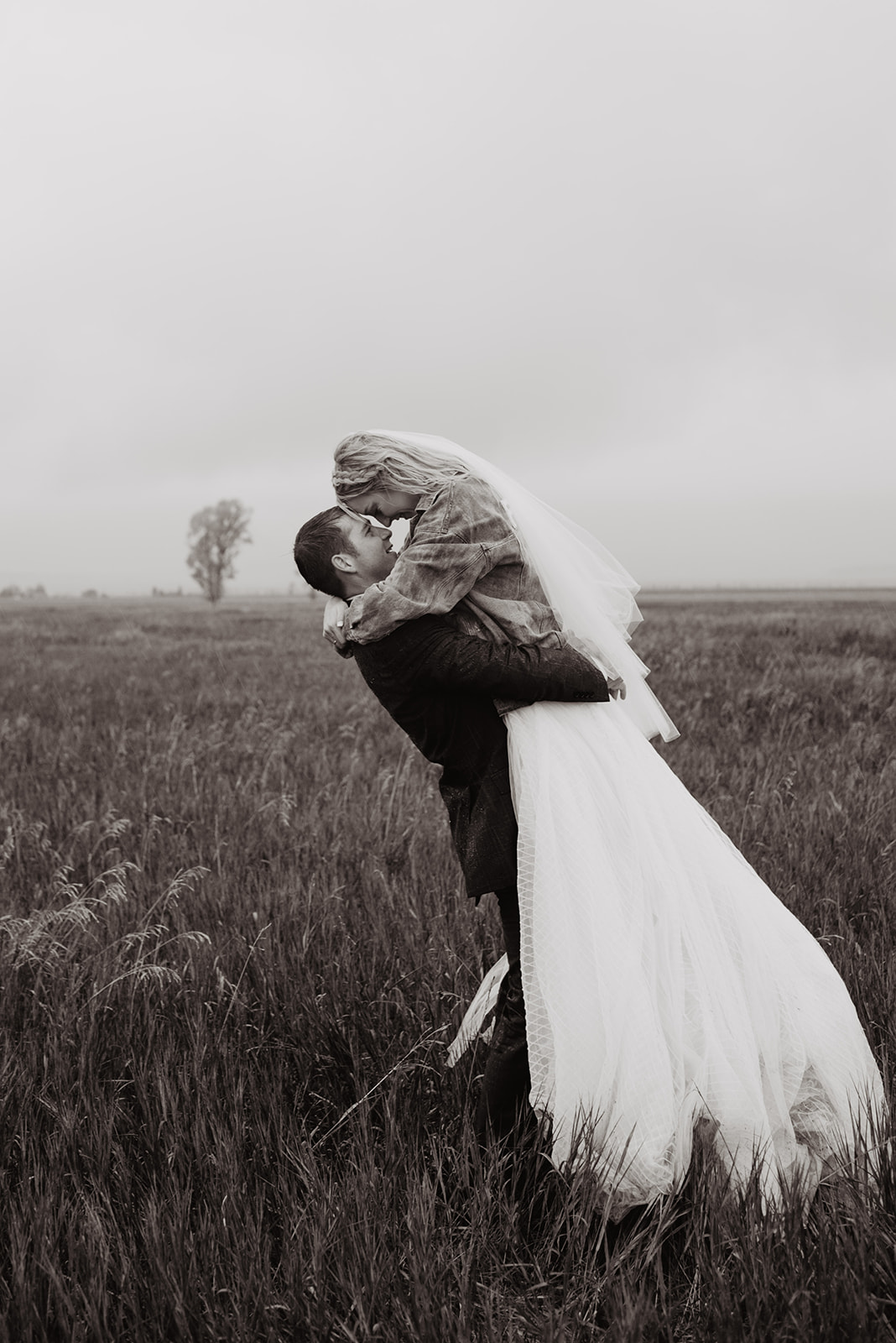 Bentwood Inn weddings with black and white image of bride and groom in a meadow with thick fog in Jackson Hole with the groom holding his bride up as they lock eyes and place their foreheads together