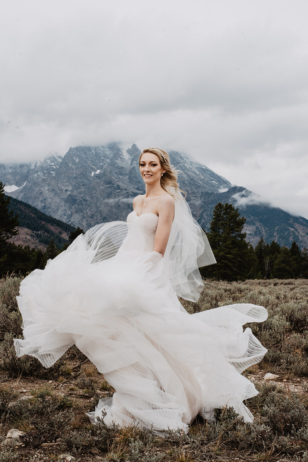 bride in a stunning a-line dress throwing her skirt in the with and twirling as she smiles in Jackson Hole wy weddings