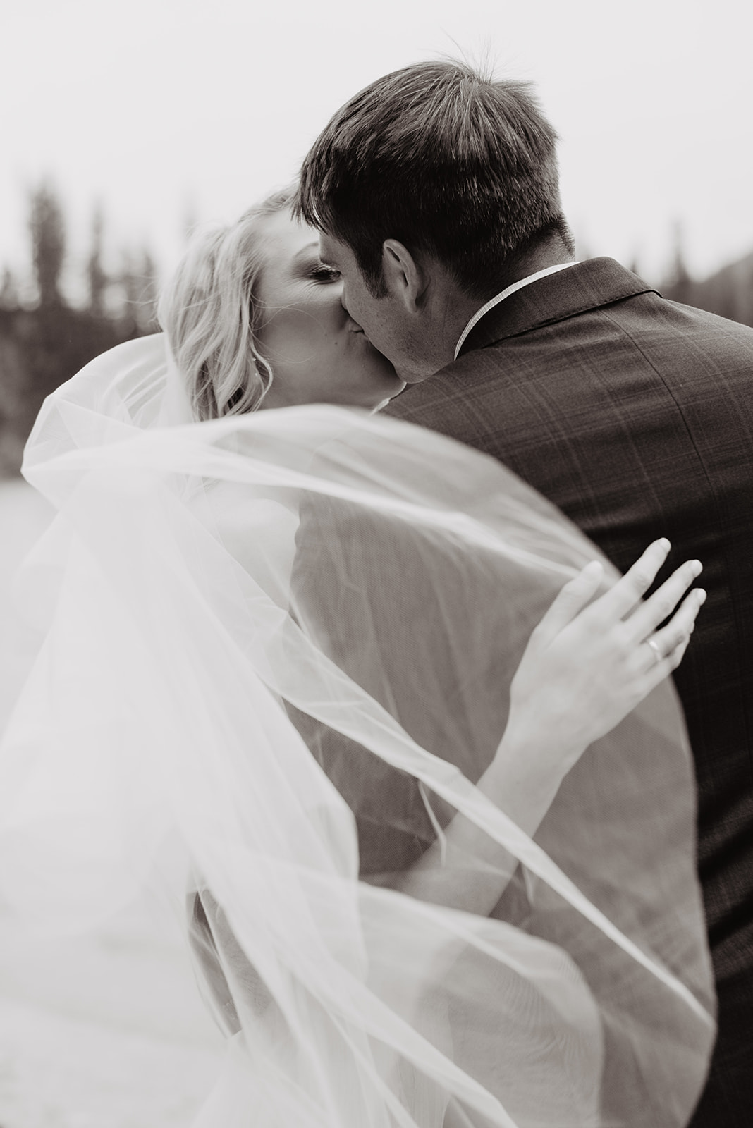Bentwood Inn weddings with romantic wedding picture in black and white with bride and groom kissing as the bride wraps her arm around her groom while her wedding veil blows in the wind past them