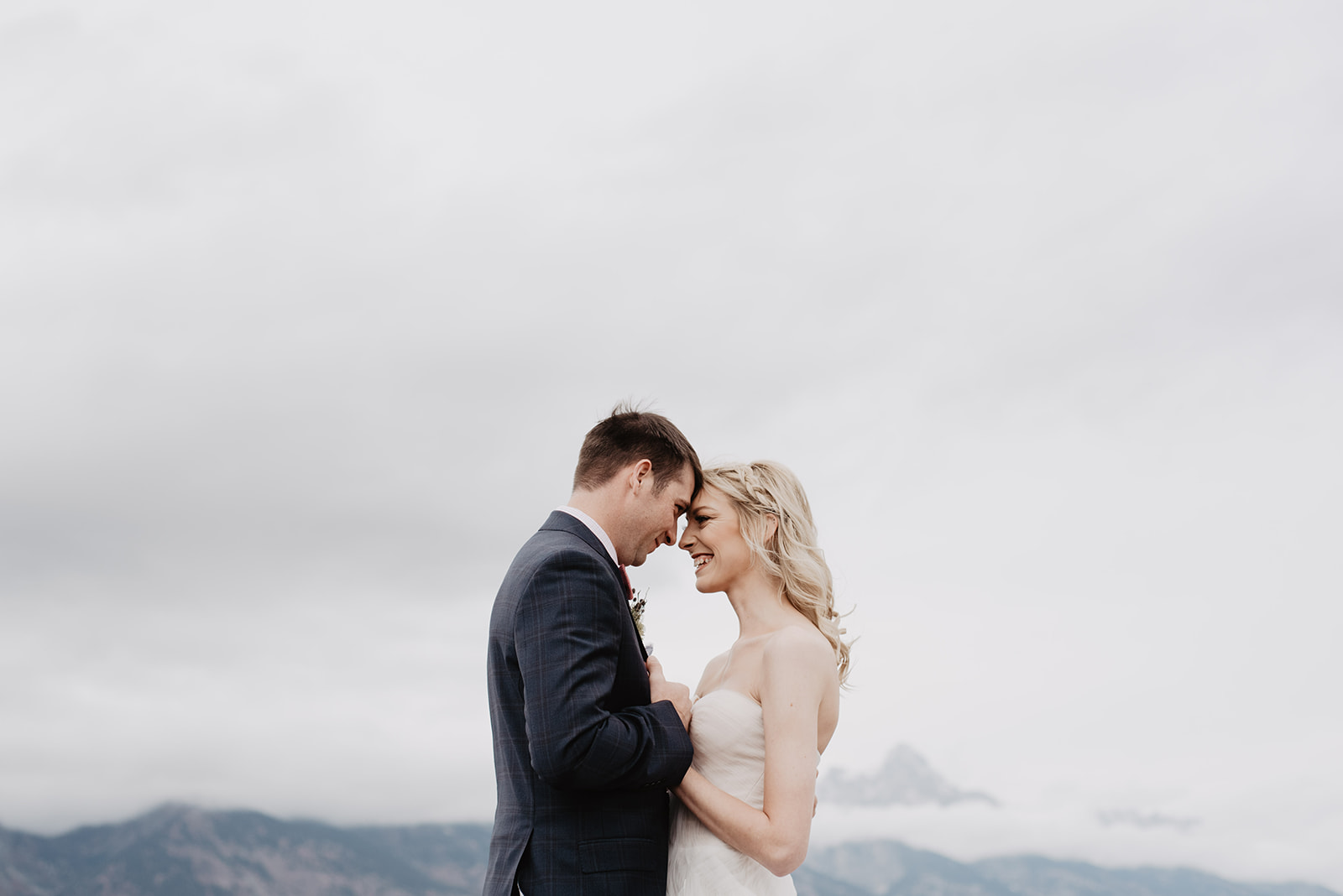 bride and groom in the clouds on a rainy day in the Grand Tetons with groom holding the brides waist as their foreheads touch, for best venues for weddings in Jackson Hole