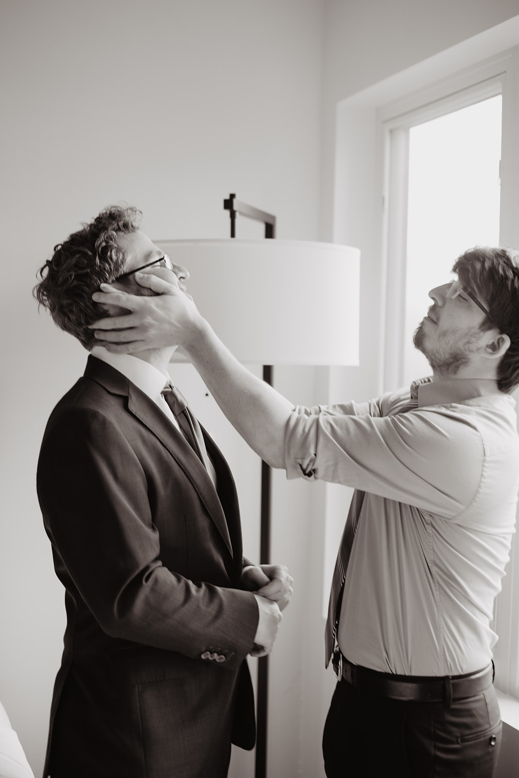black and white image of brother and the groom getting ready and being silly together and laughing