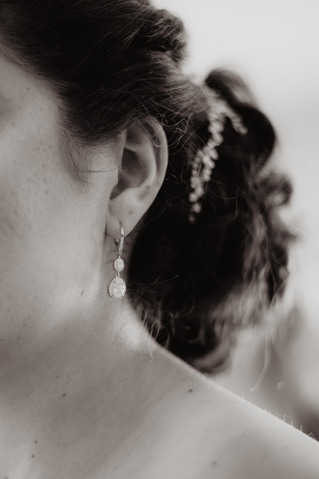 black and white detail shot of brides earring and her up-do