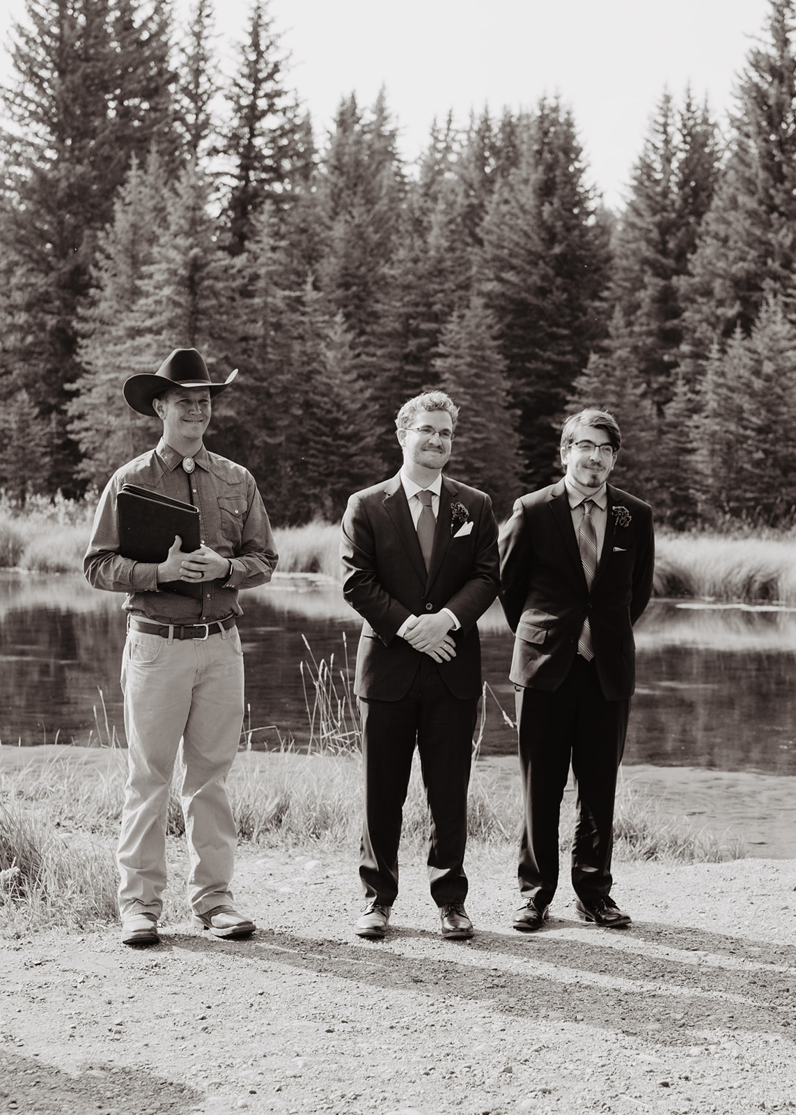 black and white image of groom standing at the natural alter with his officiant and groomsman