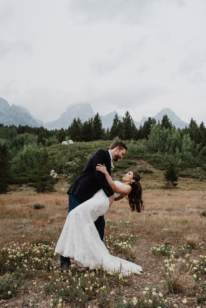 Taggart Lake adventure wedding with bride and groom dancing in a meadow with the Grand Tetons behind them for their adventure wedding with Grand Teton wedding photographers