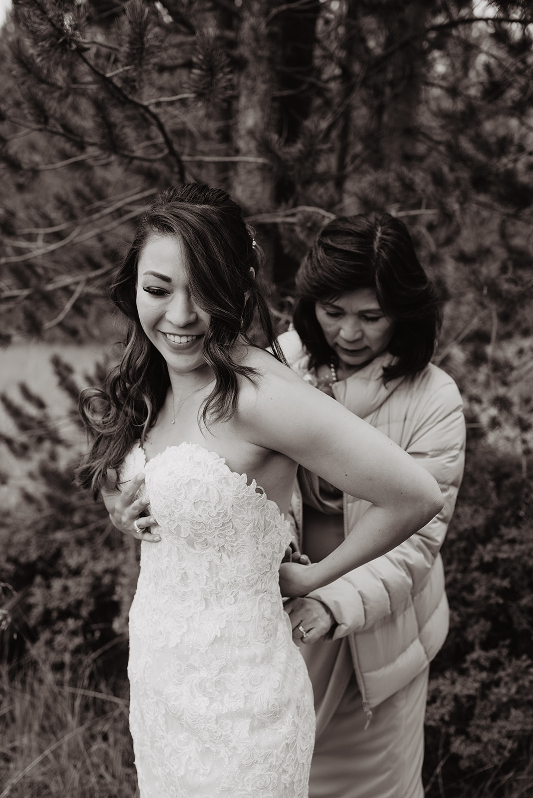 black and white photos of mom zipping up her daughters wedding dress in the Grand Tetons before her wedding ceremony