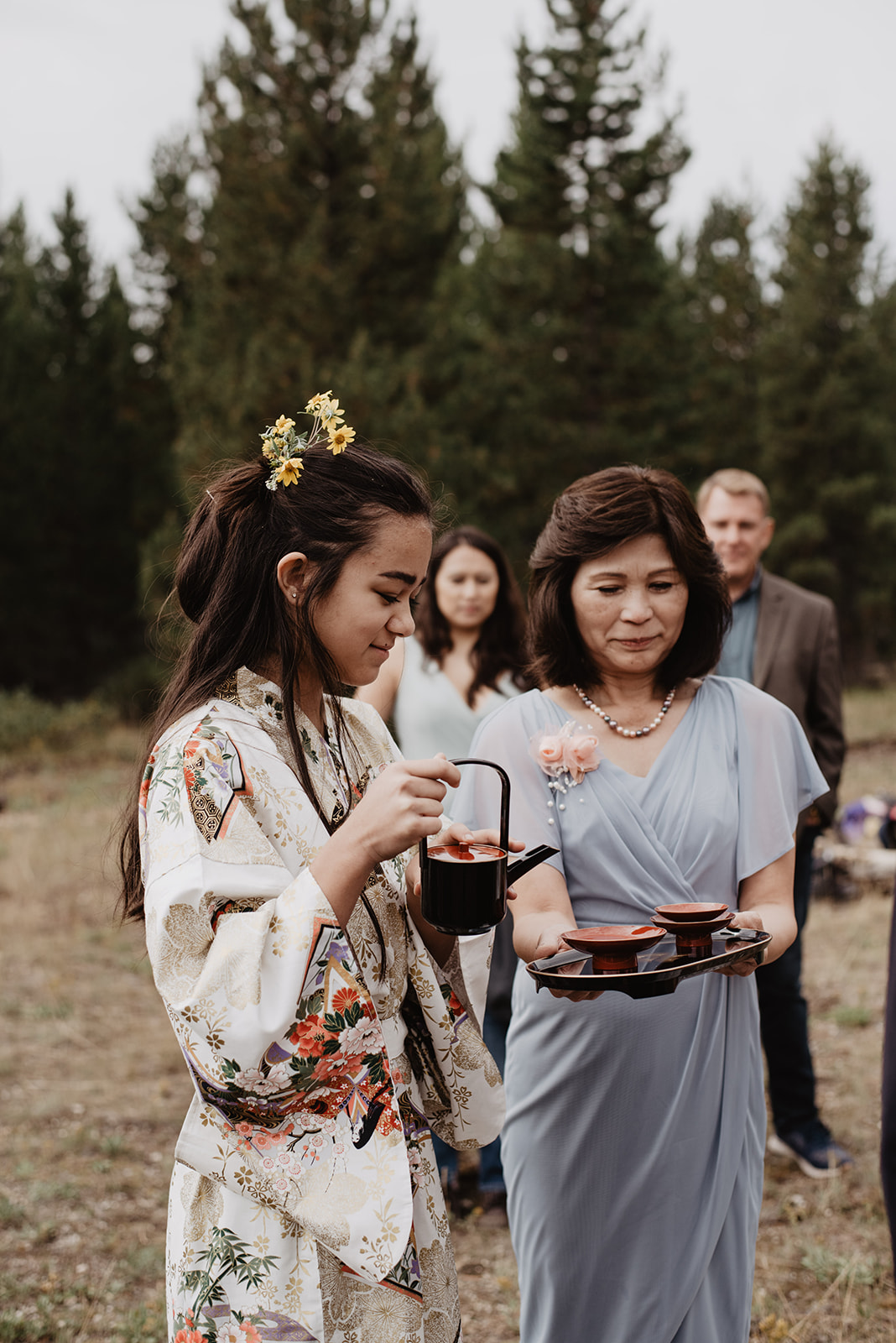 young girl in a komono pouring sake for the wedding couple in Grand tetons wedding