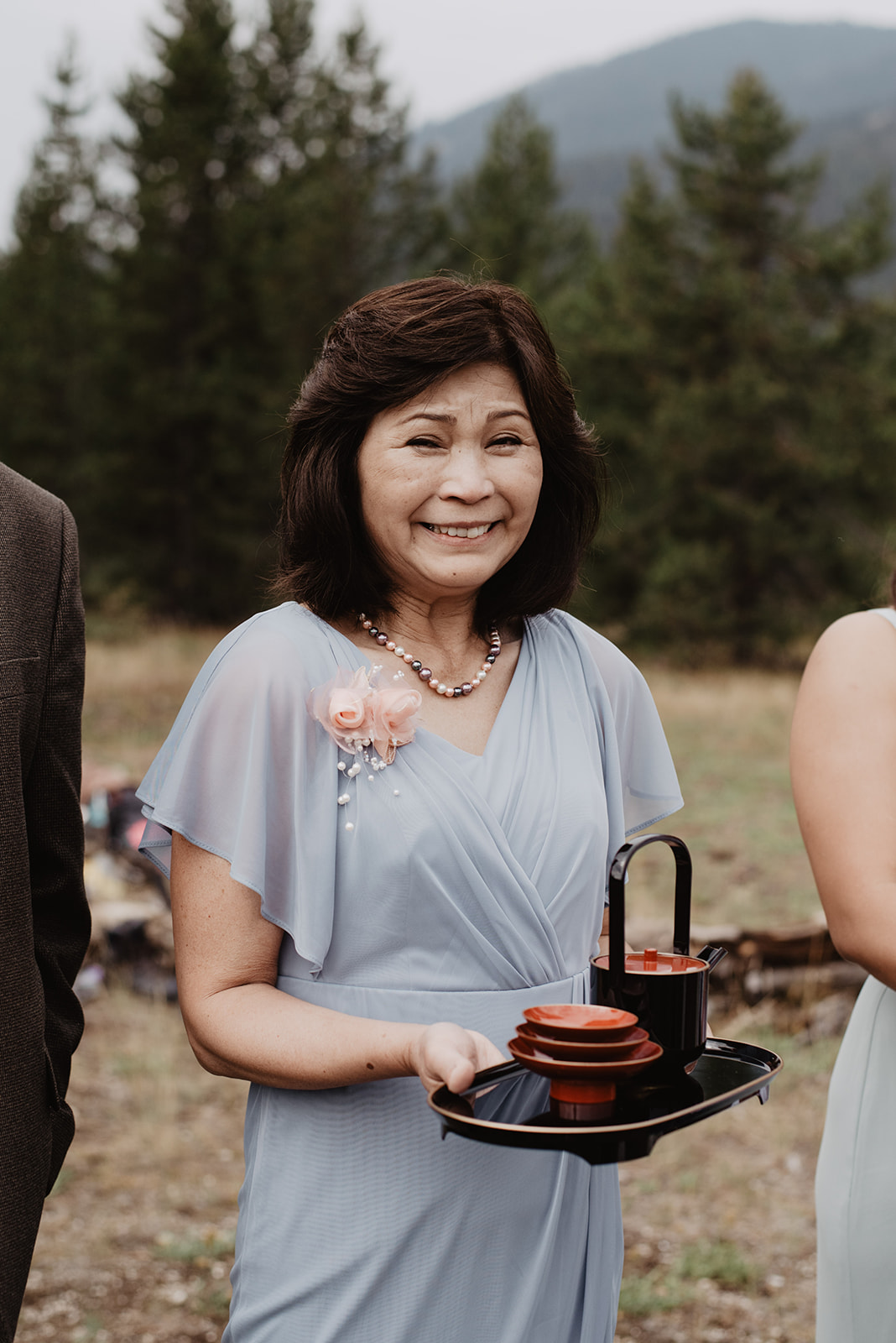 japanese mother holding a sake platter and smiling in the grand tetons for a wedding