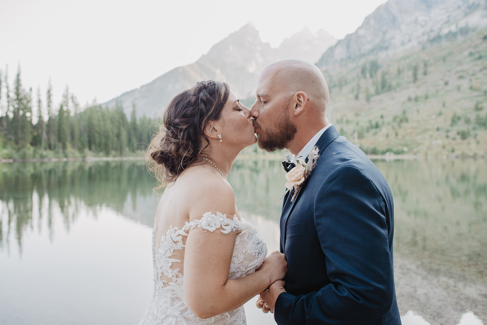 Jackson Hole wedding venues for eloping in the Tetons, bride and groom holding each others hands to their chests and kissing with the Tetons and String Lake behind them