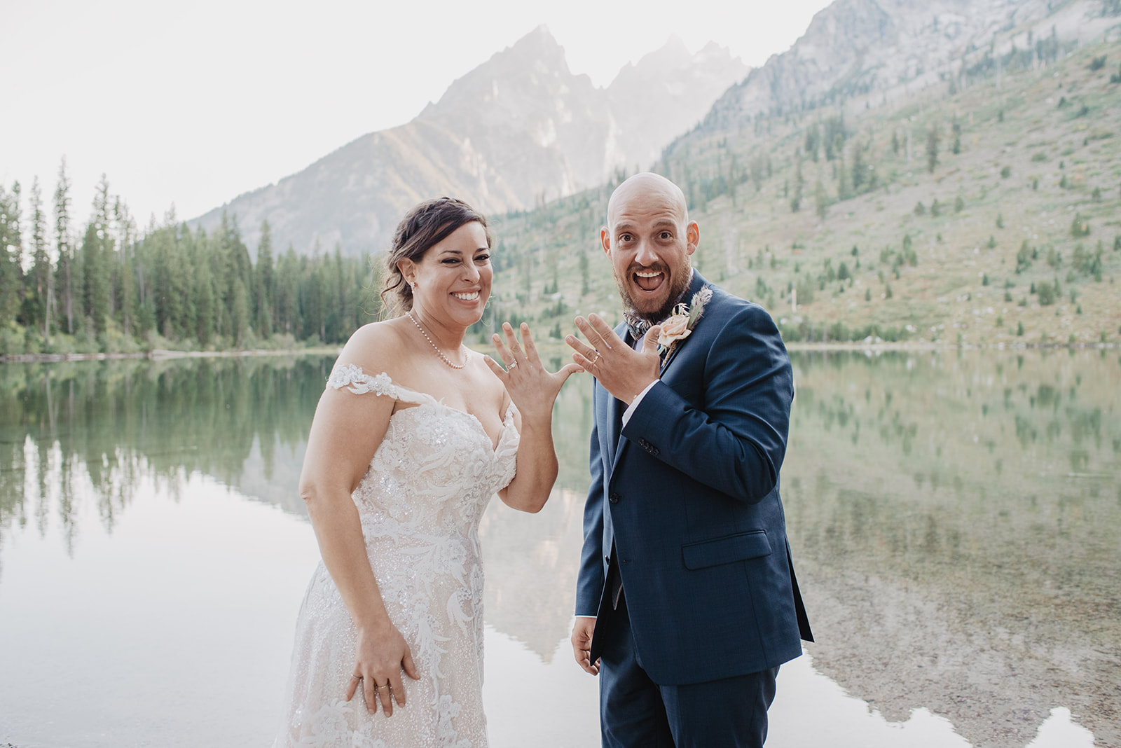 fun wedding photos in Jackson Hole with bride and groom holdin gup their hands to show their wedding rings on their Jackson Hole wedding day