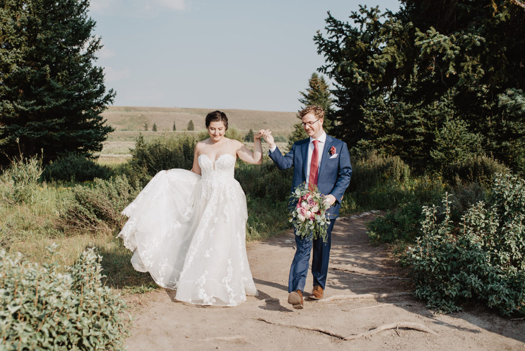 jackson hole photographer captures bride and groom dancing together on a trail in the tetons during bridal portraits 