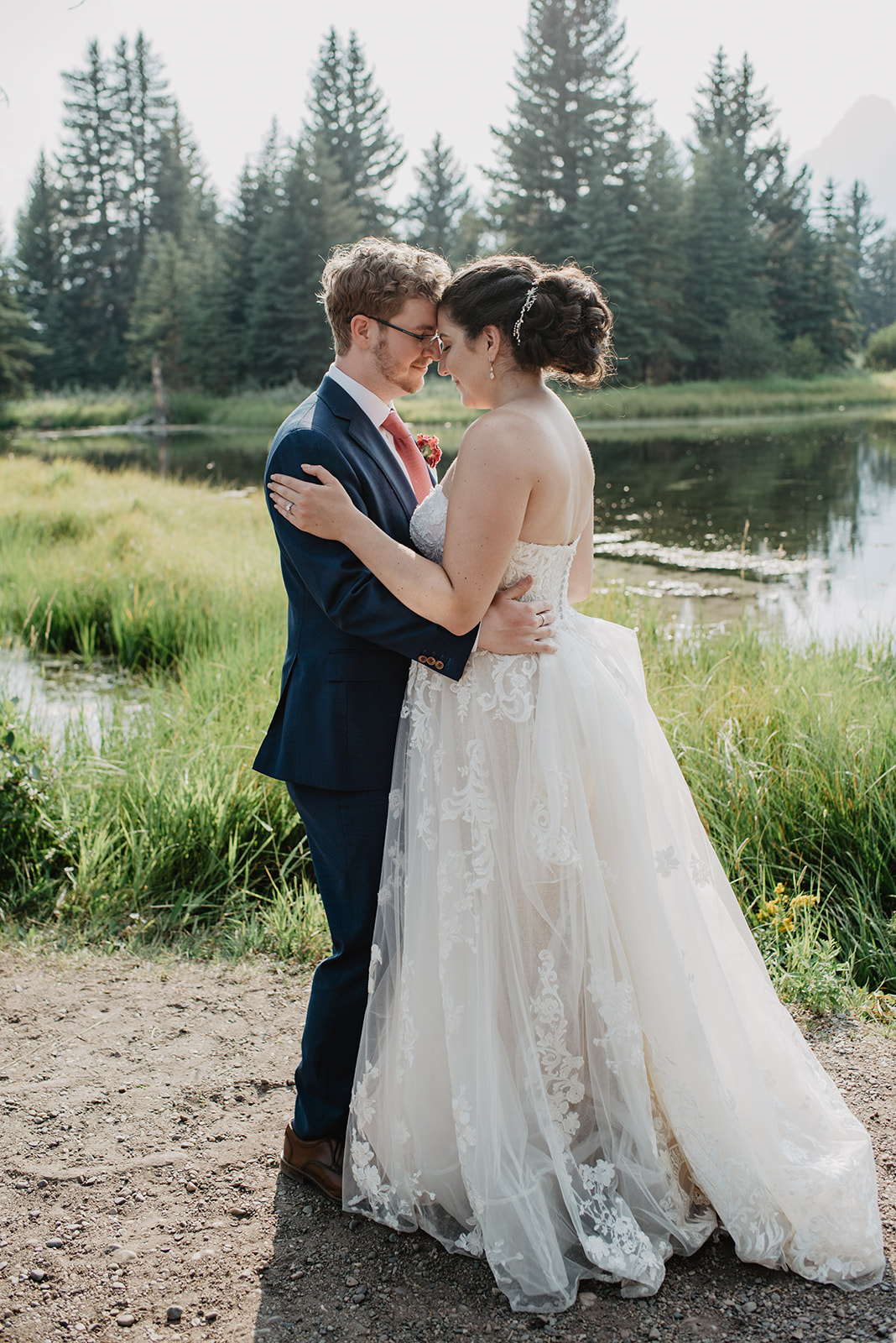 bride and groom standing next to a lake in JAckson Hole as they embrace one another and place their foreheads together
