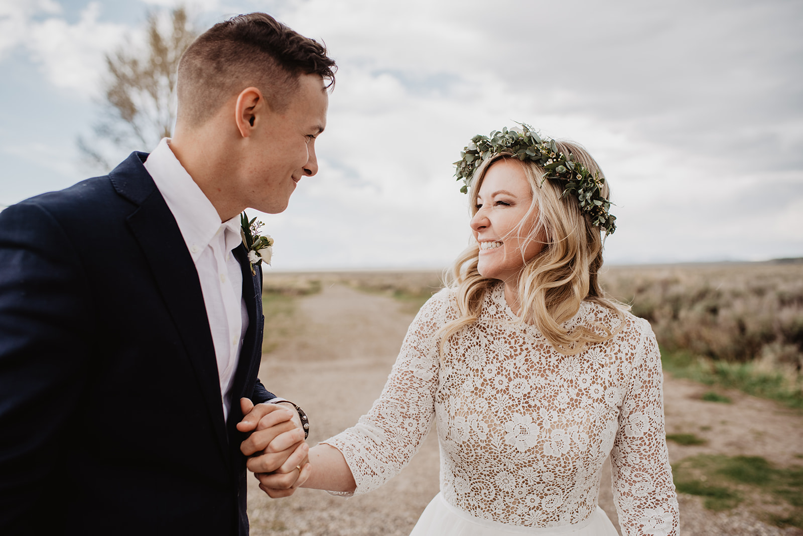 bride smiling at her groom as they hold hands and run together at Mormon Row in the Tetons for their bridal session with best Jackson Hole wedding photographer