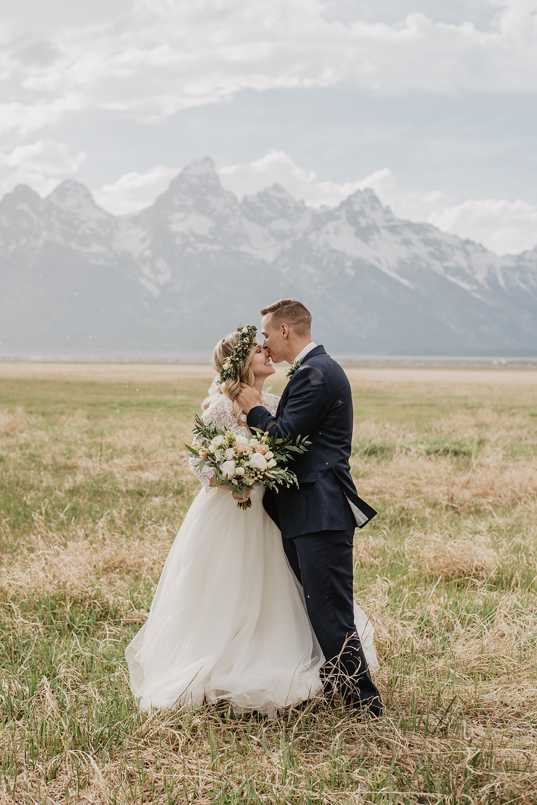 bride and groom kissing as they stand in front of the Tetons mountains in Jackson Hole for their adventure wedding captured by best Jackson Hole wedding photographer