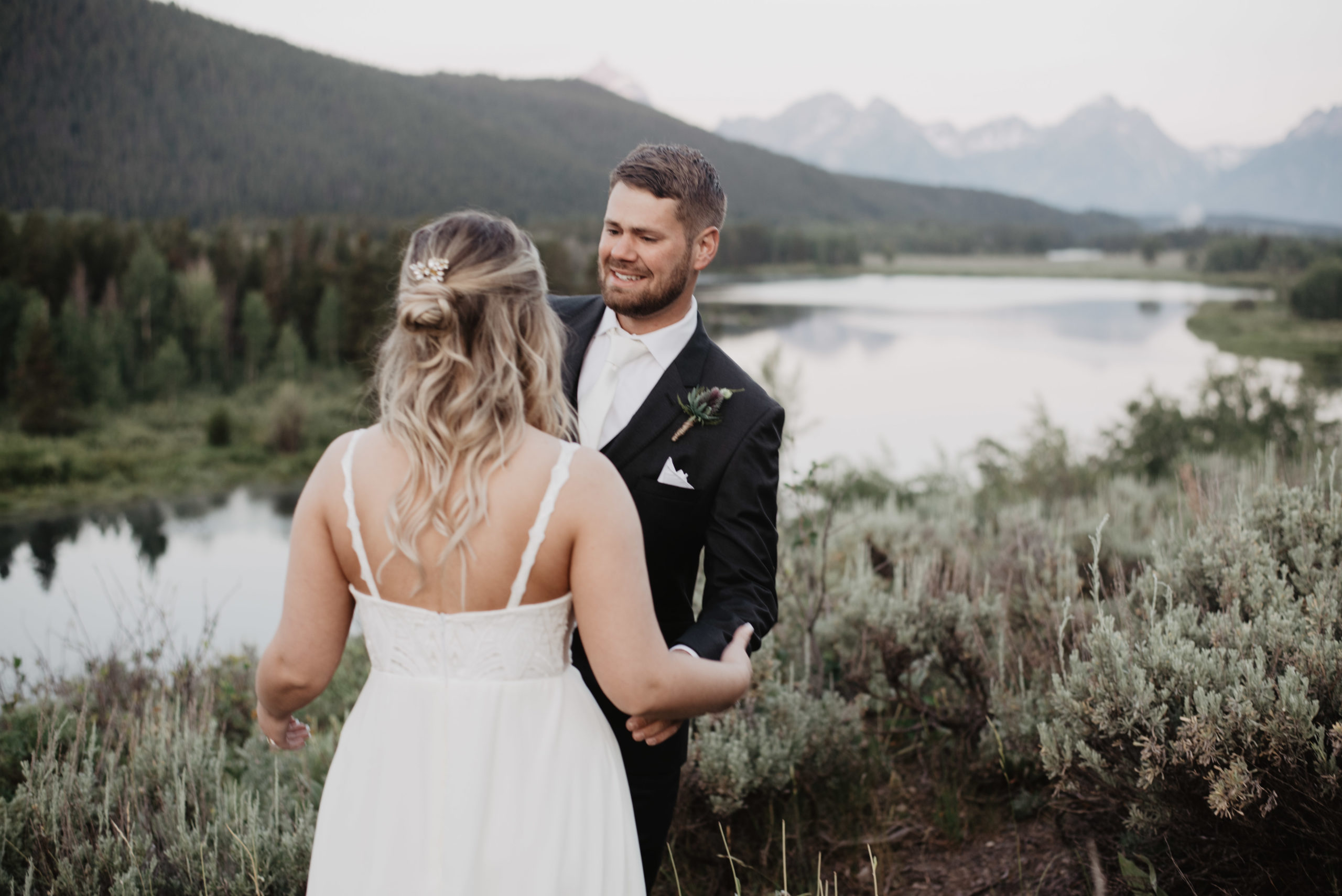 first look with bride and groom at a river in Jackson Hole for their adventure elopement with groom tearing up at his bride