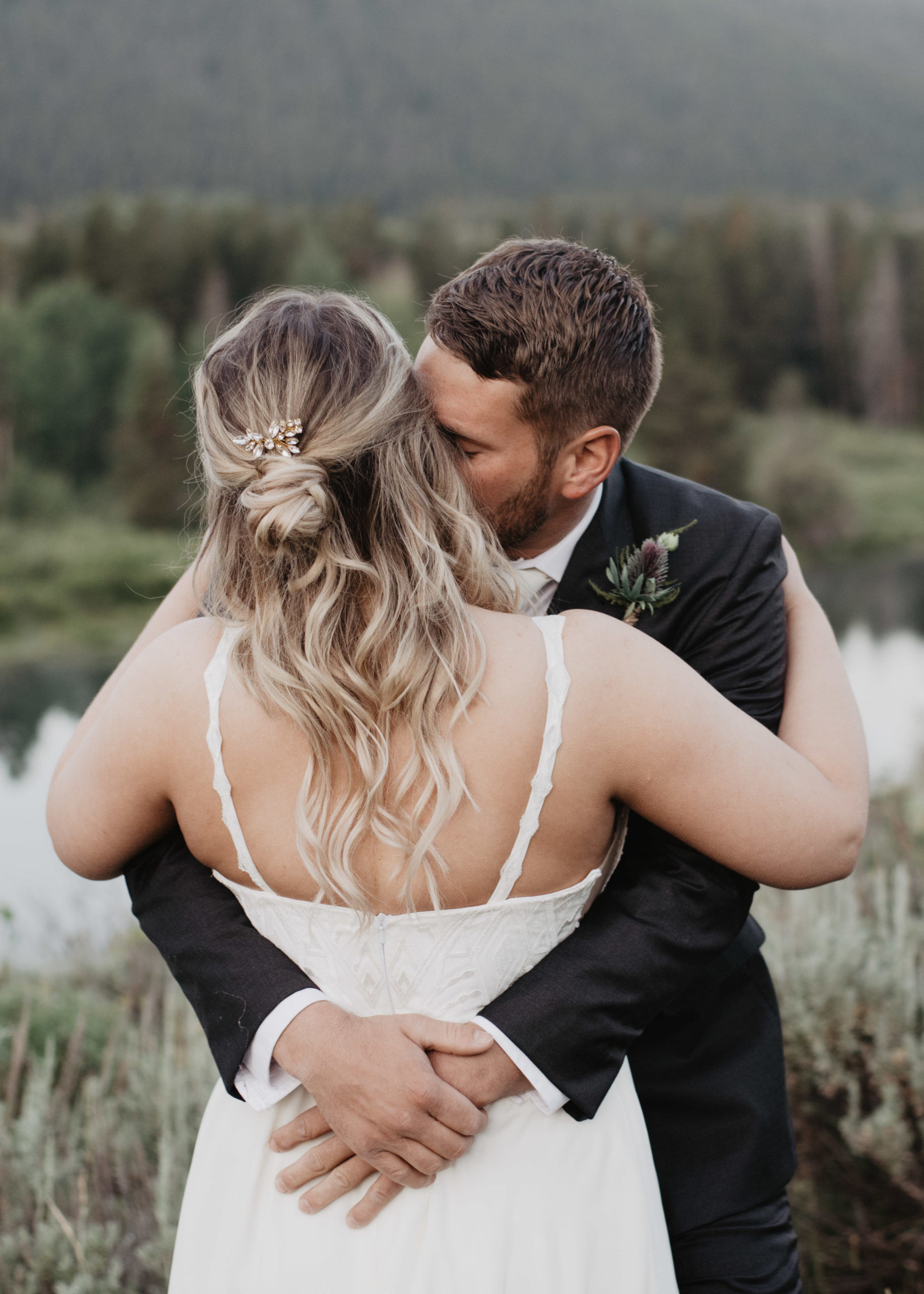 groom with his arms around his brides waist and kissing her cheek in the Grand Tetons