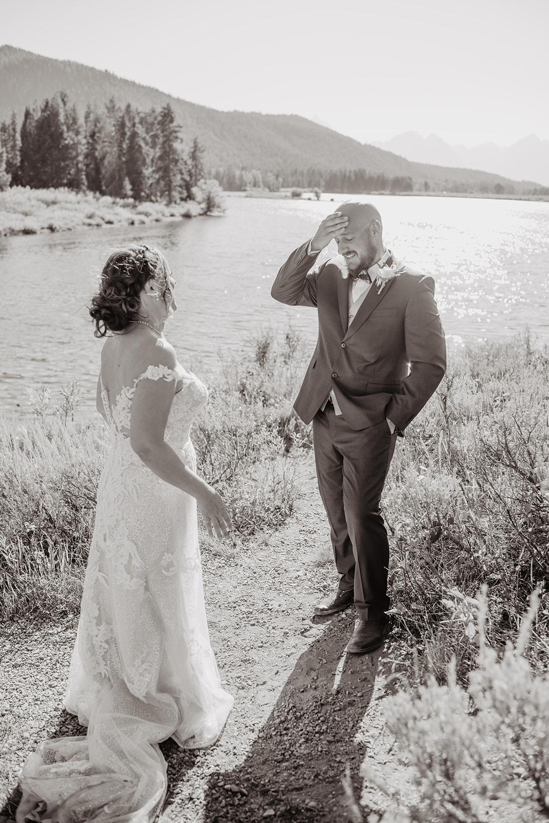 bride and groom having a first look together with groom holding his forehead in amazement for their Jackson Hole wedding on the Snake River