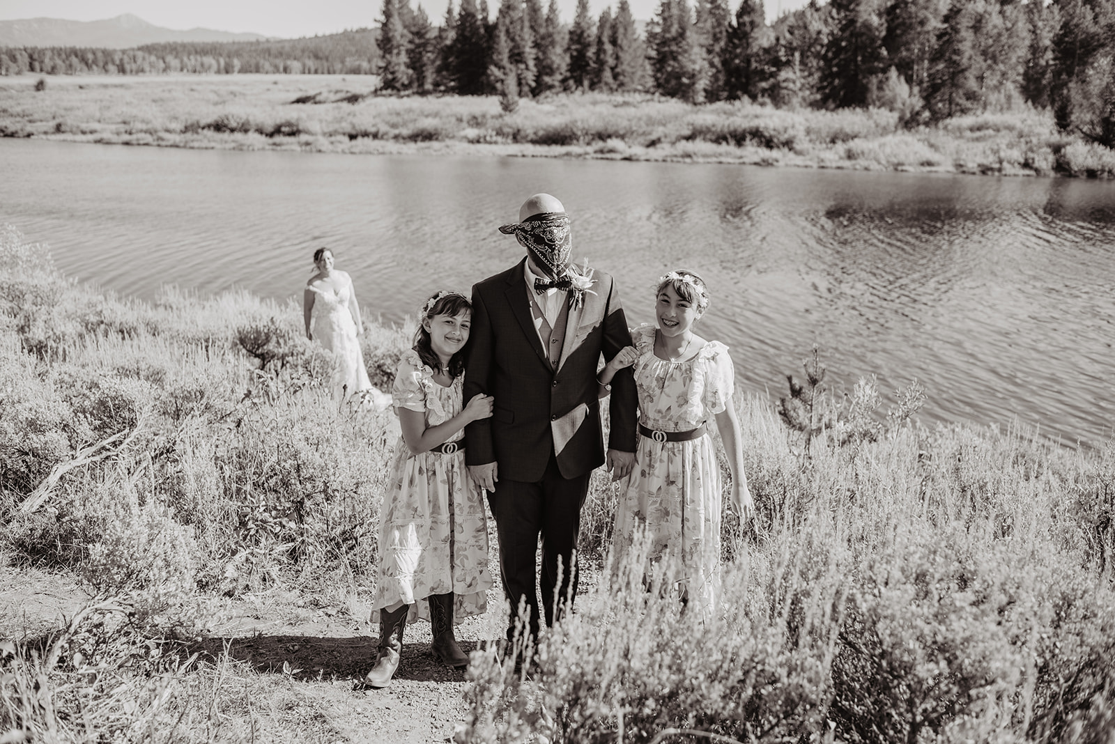black and white image of Oxbow Bend wedding in JAckson HOle with bride walking up a hill to her groom for their first look