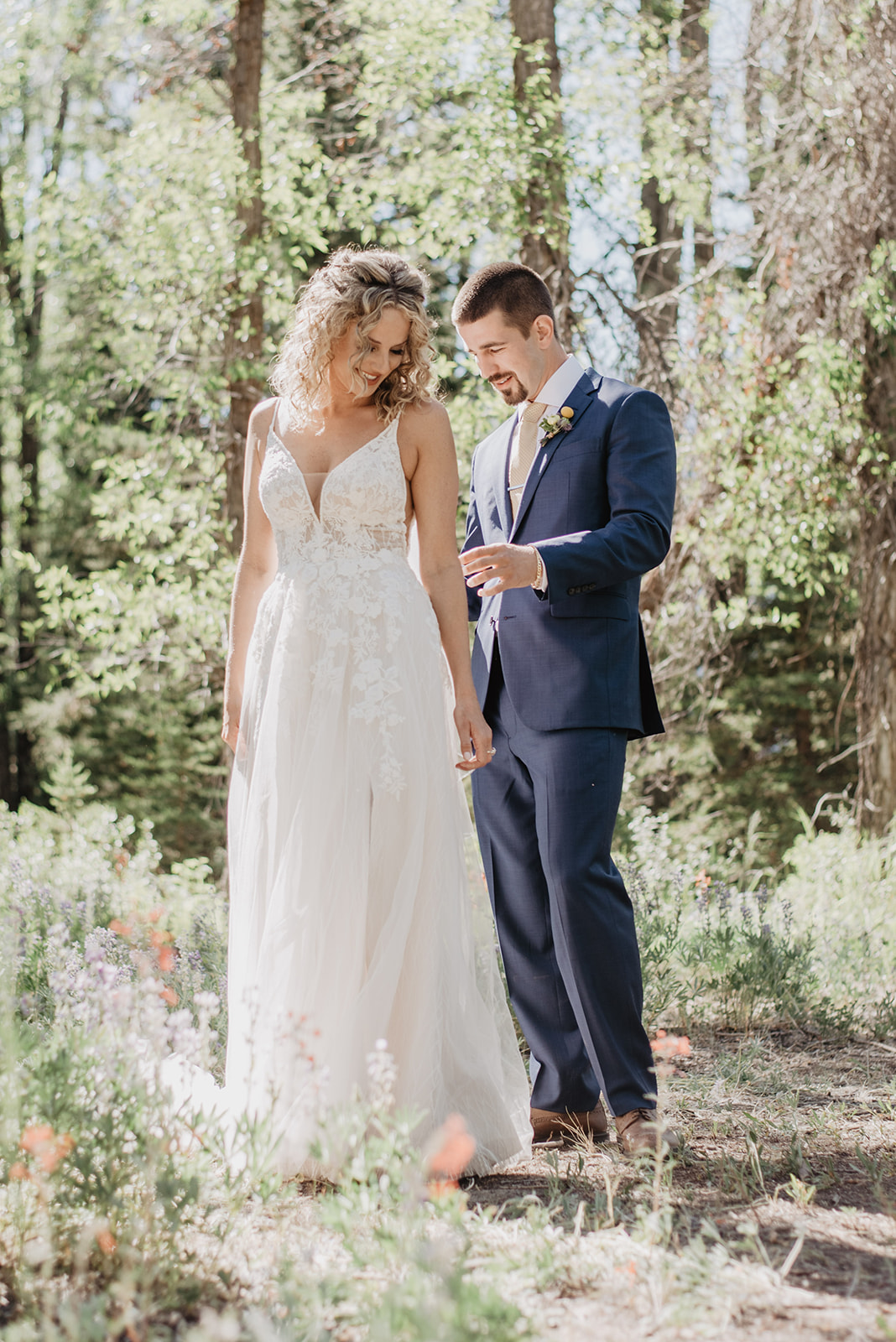 groom admiring his brides white lace and tulle wedding dress in the woods during their first look on their elopement in Jackson Hole