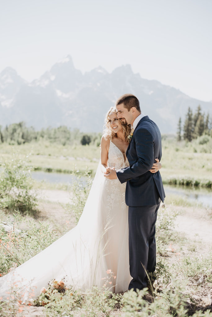 Jackson Hole photographers capture bridals in Jackson Hole for an elopement party with the bride and groom embracing each other and smiling as the Grand Tetons stand behind them