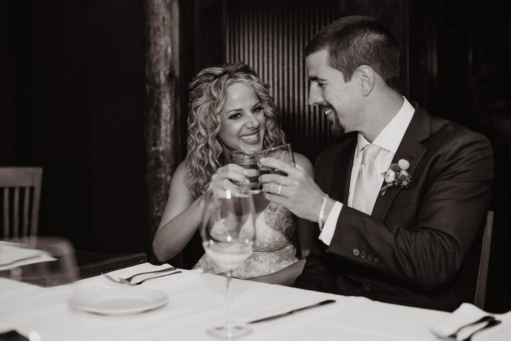 black and white image of bride and groom toasting at their Jackson Hole celebratory dinner