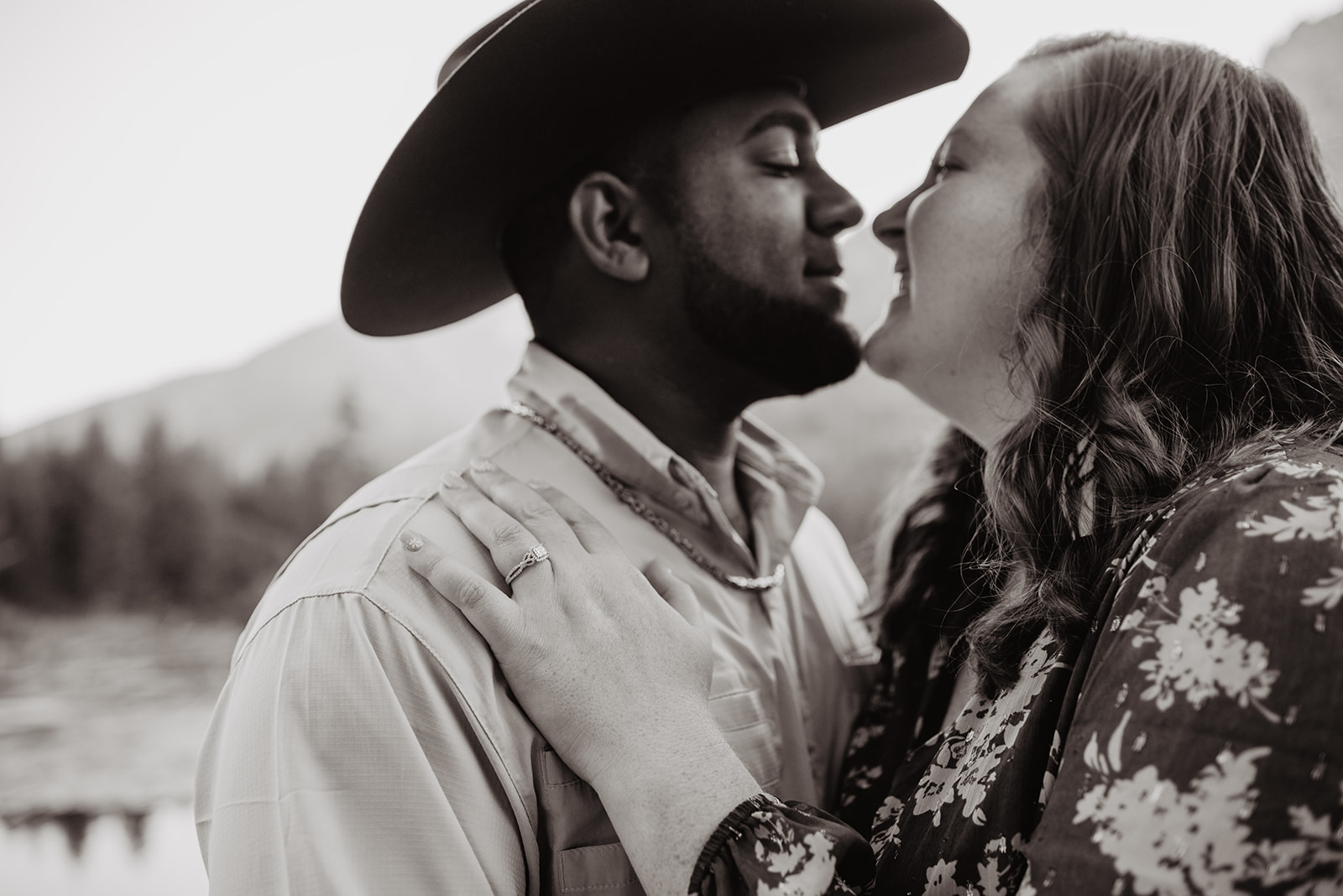 blacka nd white engagement photo of cowboy and his bride in the Grand Tetons as they lean into one another to kiss